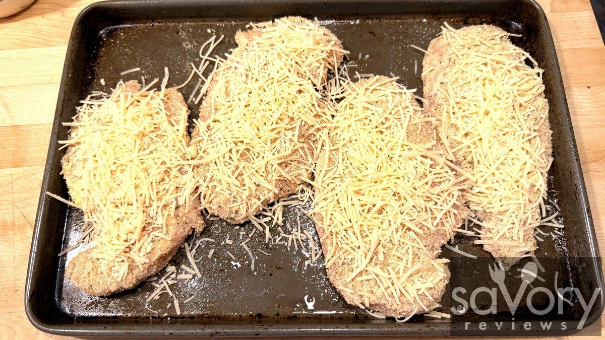 Chicken cutlets topped with shredded parmesan ready to bake